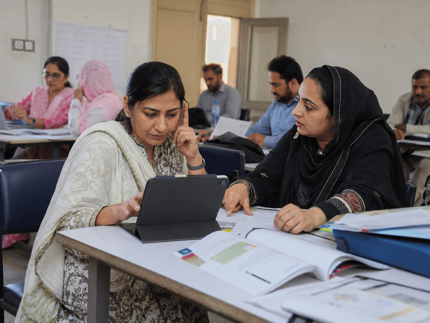 Two educators working through assessment material on a tablet and a printed workbook during a CORE Assessments session.